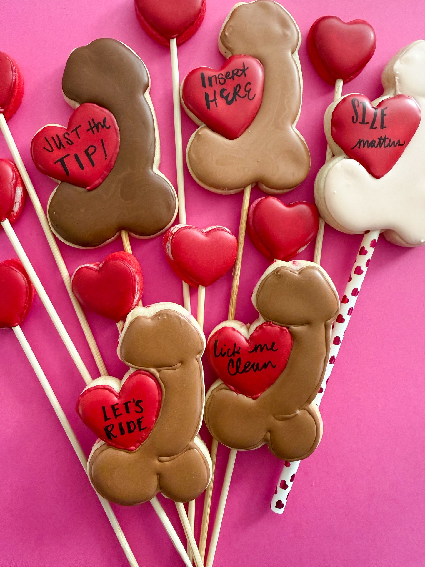 Cookie pops shaped like bones and hearts with humorous text on a pink background