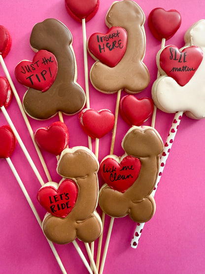 Cookie pops shaped like bones and hearts with humorous text on a pink background